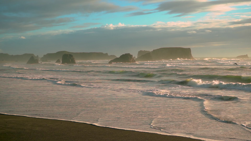 Dramatic seascape with sea stacks in Bandon, Oregon Coast, during a beautiful and dramatic sunset. Slow motion footage, camera zooming out.