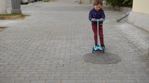 Child riding scooter on green kick board.