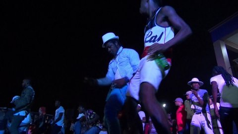 KINGSTON, JAMAICA - CIRCA JUNE 2017 : Scenery of outdoor street night club. Man and woman enjoying dance, popular night life for many Jamaican people. Reggae and hip hop music are played by DJ.