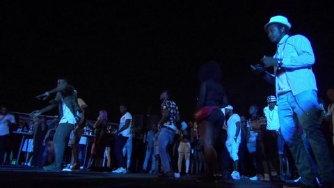 KINGSTON, JAMAICA - CIRCA JUNE 2017 : Scenery of outdoor street night club. Man and woman enjoying dance, popular night life for many Jamaican people. Reggae and hip hop music are played by DJ.
