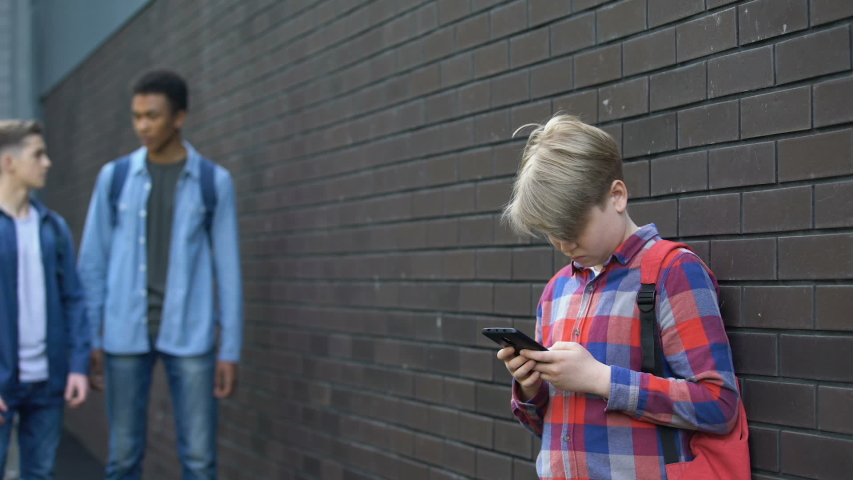 Cruel students bullying boy in backyard, punching head, physical intimidation