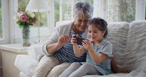 little girl using smartphone with grandmother having video chat waving at family sharing vacation weekend with granny chatting on mobile phone relaxing at home with granddaughter 4k