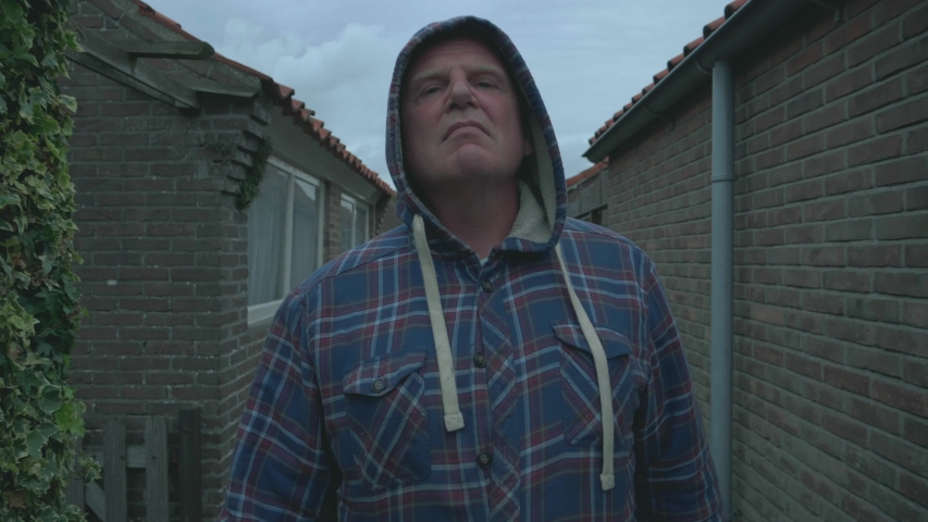 Nice portrait of an angry and aggressive attacking European man that is walking through an alley of a residential area. 4K cinematic footage.