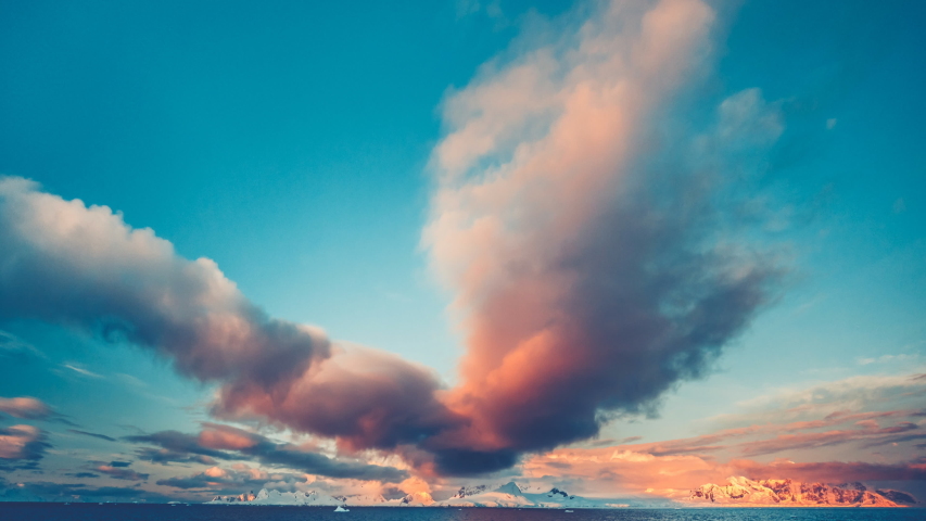 Antarctic Sunset in Wild Nature. Beautiful colorful cloudy sky. Bright orange clouds and mountains in ocean water. Majestic polar landscape. Holidays and recreation. Travel background. Time lapse 4K