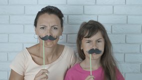 Woman with child in false mustache. Cheerful mother with daughter with false mustache. - Powered by Shutterstock - Get 15% off with code: PIKWIZARD15
