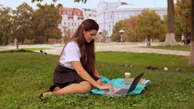 caucasian student has video call with friend sitting on the lawn near tree. young woman with long hair enjoy break outdoors