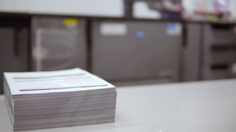 female worker brings printed brochures corrects a stack of papers