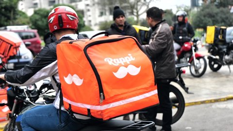 Lima, Peru - July 7 2019: Man riding motorbike working for Rappi food delivery service. Sharing collaborative economy concept in South America.