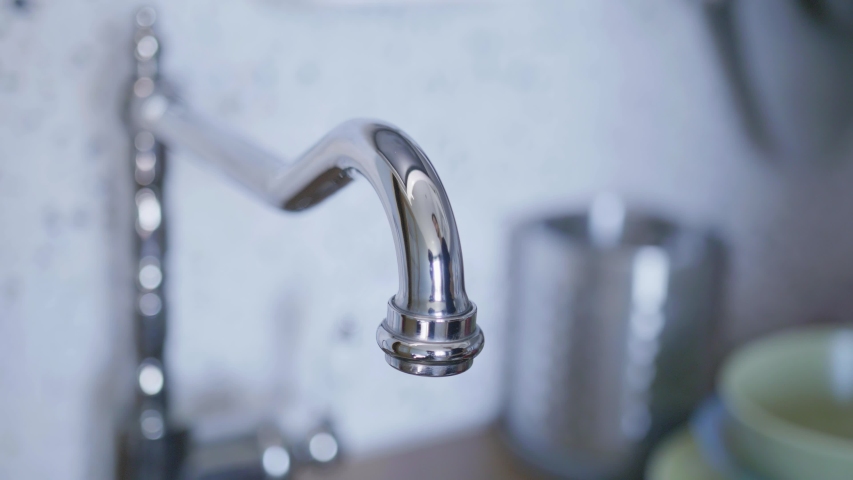 View of clean tap water for washing dishes starts flowing from long, cute, new bright, steel tap in light kitchen when someone turned it on in daylight. | Shutterstock HD Video #1032801227