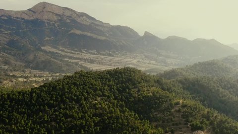 Aerial pan of misty dreamscape with green hills and terraced valley, Alicante Spain