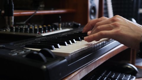 Hands playing on piano electronic keyboard with digital watch. Music recording studio concept. Musician producing song in studio. Song recording process.