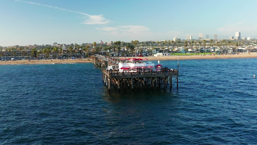 Aerial view over Newport Beach in coastal Orange County, California on a sunny day from above with the ocean, pier and harbor in view.