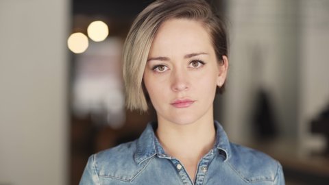 Head and shoulders portrait of beautiful young Caucasian woman with short hair looking at camera with blank facial expression