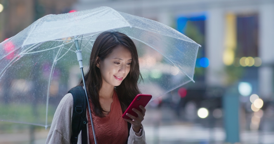 Woman use of mobile phone and hold with umbrella in the evening