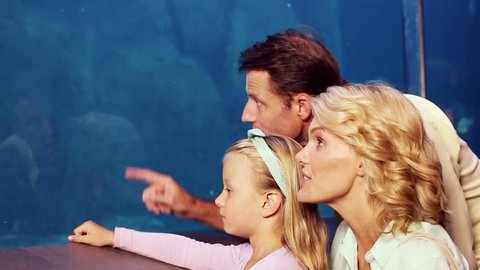 Happy family looking at fish at the aquarium
