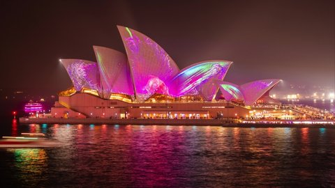 SYDNEY, AUSTRALIA - June 15 2019: Traffic on the water in front of the Sydney Opera House, Sydney Harbour during the Vivid Light Festival.  Timelapse shot straight on from Circular Quay.