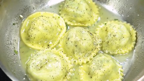 Extreme close up of fresh ravioli in a pan with sauce. Stirring Dumplings in a pan. Cooking Ravioli in boiled water. Boiling handmade pasta white sauce. Italian spaghetti. Close up cooking pasta. 