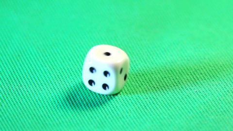 A single ivory-colored six-sided die (dice) rolls, bounces and spins in slow motion (one tenth speed) on a green surface before settling on the number one. Suitable for green-screen chroma-keying.