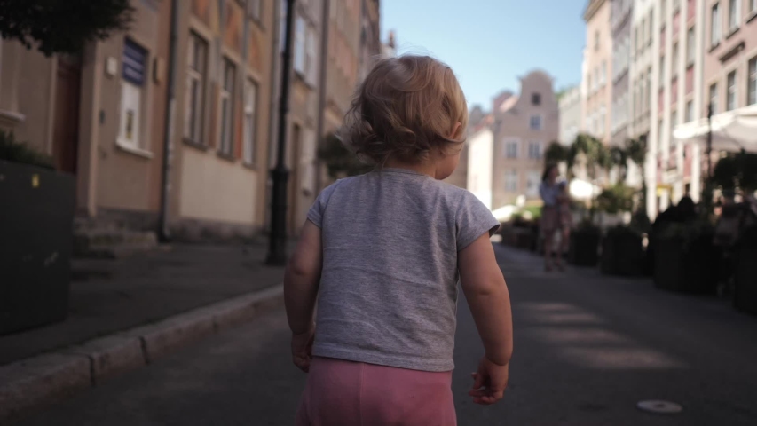 little curly blonde girl travels walking down the street 