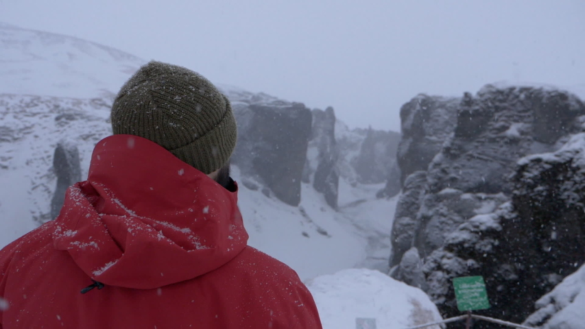 Man looking at view in Iceland with snow falling in slow motion
