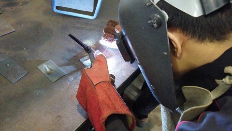 Welder performing Tungsten Inert Gas welding process (TIG) on metal plate. TIG welding uses the heat generated by an electric arc struck between a non-consumable tungsten electrode and the work piece.
