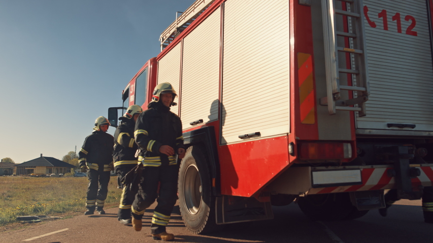 Rescue Team of Firefighters Arrive at the Crash, Catastrophe, Fire Site on their Fire Engine. Firemen Grab their Equipment, Prepare Fire Hoses and Gear from Fire Truck, Rush to Help Injured People. Royalty-Free Stock Footage #1032836144