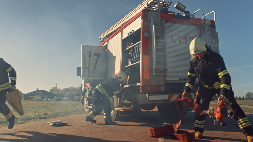 Rescue Team of Firefighters Arrive at the Crash, Catastrophe, Fire Site on their Fire Engine. Firemen Grab their Equipment, Prepare Fire Hoses and Gear from Fire Truck, Rush to Help Injured People. Royalty-Free Stock Footage #1032836144