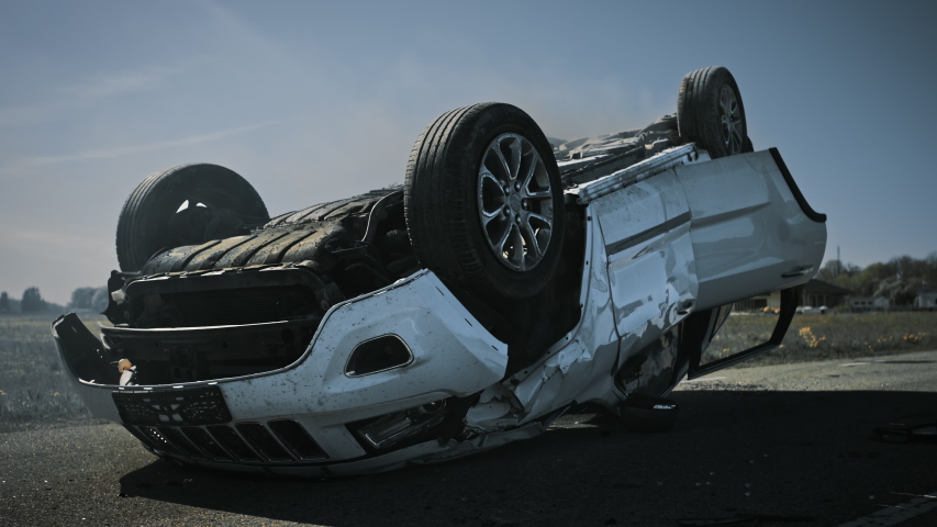 Horrific Traffic Accident, Rollover Smoking and Burning Vehicle Lying on its Roof in the Middle of the Road after Collision. Daytime Crash Scene with Severely Damaged Burning and Smoking Car Royalty-Free Stock Footage #1032836285