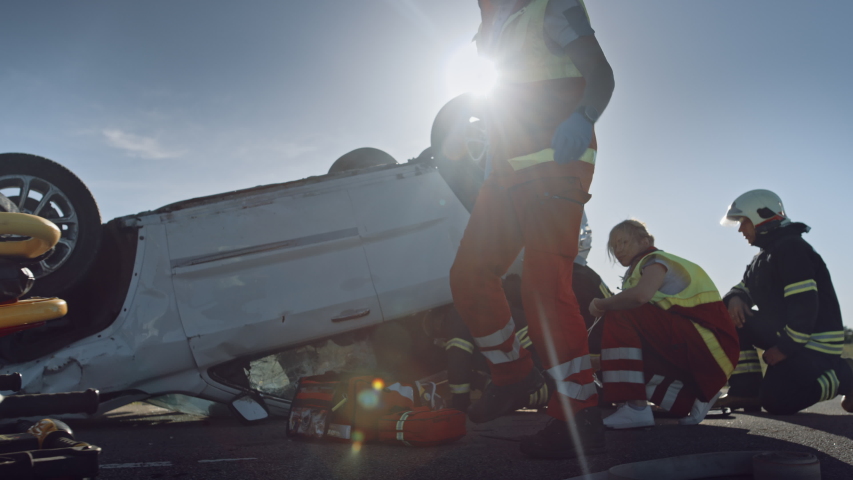 On the Car Crash Traffic Accident Scene: Paramedics Giving First Aid Oxygen Mask to Female Victim of the Accident. Firefighters Extinguish Fire and Use Hydraulic Cutter to Free Other Passengers Royalty-Free Stock Footage #1032836288