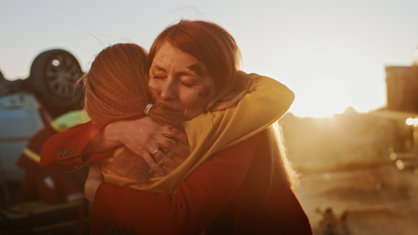 Injured Mother and Young Daughter Reunite After Terrible Car Crash Traffic Accident, They Hug Happily. In the Background Through Smoke and Fire, Courageous Paramedics and Firefighters Save Lives Royalty-Free Stock Footage #1032836312