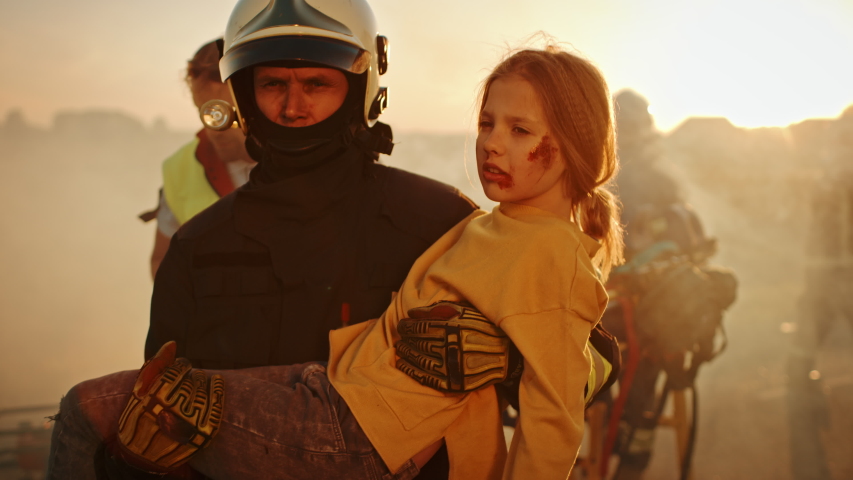 Brave Firefighter Carries Injured Young Girl to Safety. In the Background Car Crash Traffice Accident with Courageous Paramedics and Firemen Save Lifes, Fight Fire | Shutterstock HD Video #1032836351