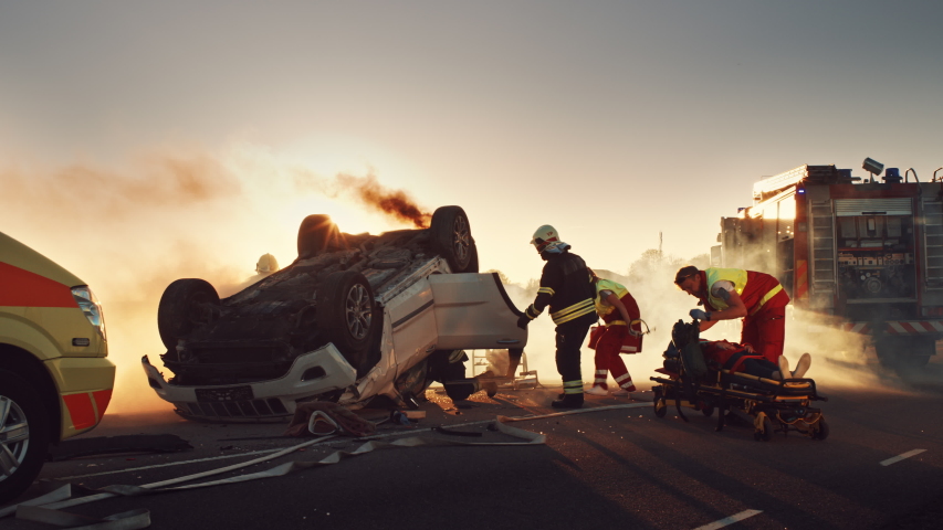 On the Car Crash Traffic Accident Scene: Paramedics and Firefighters Rescue Injured Victim Trapped in the Vehicle. Extricate Person Using Stretchers, Give First Aid and Transport Them to Hospital Royalty-Free Stock Footage #1032836357