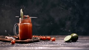 ground pepper falling in glass with bloody mary cocktail on black