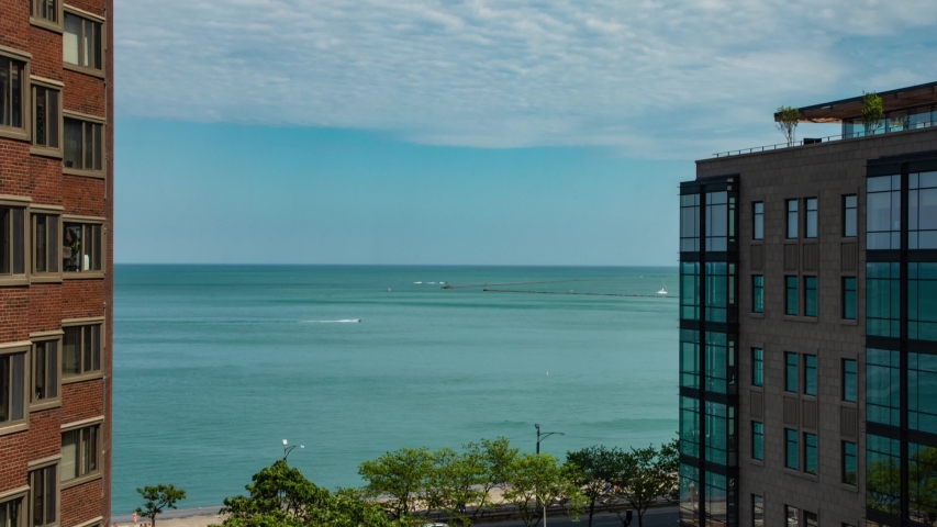 Time lapse zoom back of clouds, aqua blue water of Lake Michigan, traffic passing