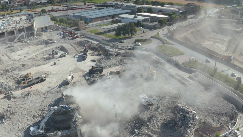 Drone flying over a big city construction demolition site, pointing at bulldozer and crane in action.