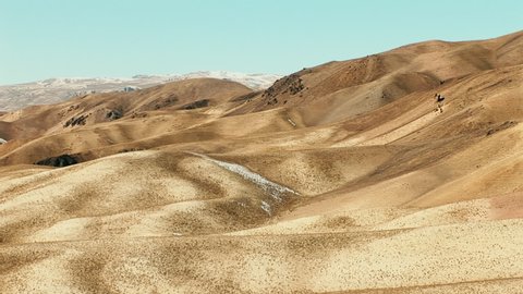 Panning shot of the surreal desert landscape of Bamyan Afghanistan with distant frozen mountain peaks - Shah Foladi