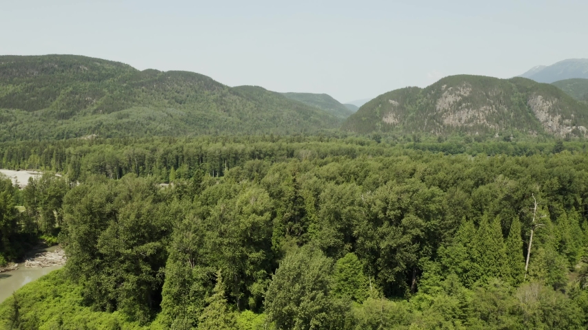 An aerial, cinematic, moving view of the surrounding hills and mountains, shot in Terrace, B.C. Canada during the summer months on a sunny day.