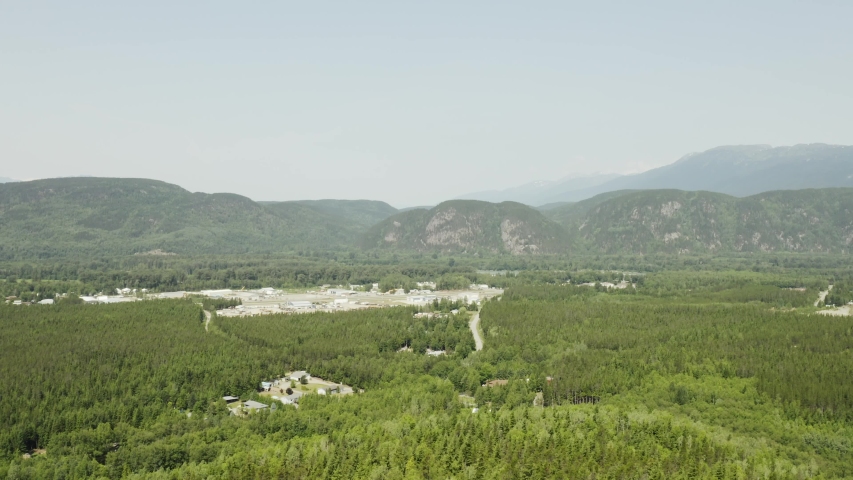 An aerial, cinematic, moving view of the outskirts of town, shot in Terrace, B.C. Canada during the summer months on a sunny day.