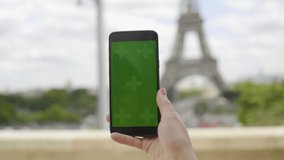 Girl using smartphone with Green Screen at Eiffel Tower, Swiping and Scrolling on Touch Screen with Tracking Markers. Browsing Internet, Watching Media Content, Videos, Blogs, Social Networks. 4K UHD.