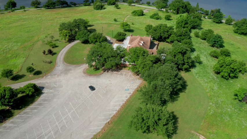 An epic aerial shot orbiting around White Rock Lake park Dallas, Texas. Fields of flowers and trees surround the building.