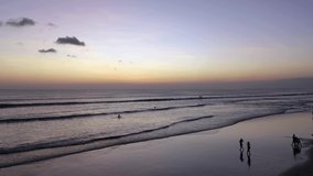 Aerial video from a drone in Bali. Drone flies at sunset, big waves on the beach of Kuta.