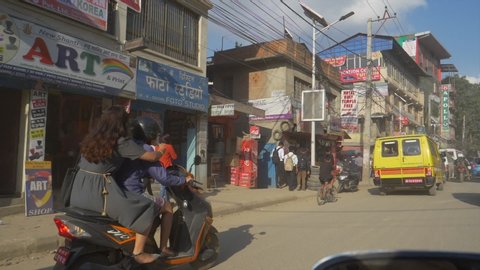 KATHMANDU, NEPAL - SEPTEMBER 2018: SLOW MOTION: Unrecognizable young kid on a bicycle rides down the bumpy road filled with old cars. Traffic congests in the weathered city streets of Kathmandu.