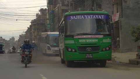 KATHMANDU, NEPAL - SEPTEMBER 2018: SLOW MOTION, CLOSE UP: Cars and motorbikes polluting the air in a crowded third world country. Thick black smoke coming from green bus pollutes the air in Kathmandu.