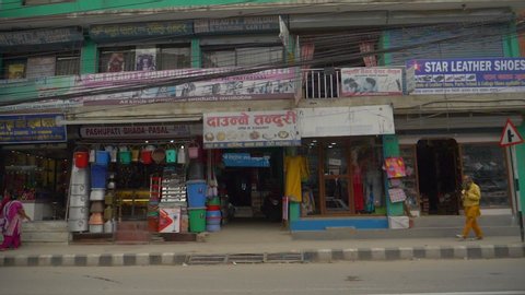 KATHMANDU, NEPAL - SEPTEMBER 2018: SLOW MOTION: Driving past tourist stores facing the crowded roads in Kathmandu. Scenic shot 3rd world country city streets full of traffic polluting the environment