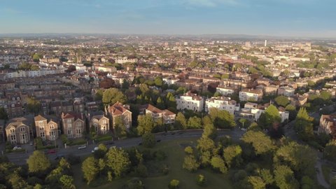 Aerial flyover green tree lined city streets of Bristol, England, drone shot at sunset golden hour