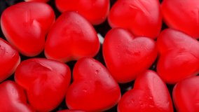 Heart shaped jelly candy rotated love background. Red jelly sweets candies rotation backdrop. St. Valentines, love, marriage hearts background. Closeup. Love, wedding concept. Slow motion 4K UHD video