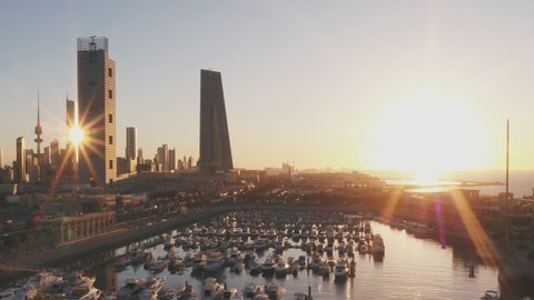 Aerial view at sunset on the pier of boats on the background of modern buildings in the city of Kuwait.