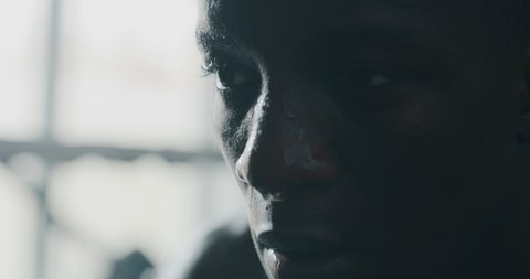Cinematic slow motion close up shot of a professional young sweaty african man is after practicing shadow boxing work out in a ring. 