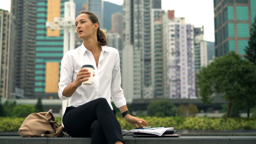 Pretty businesswoman drinking coffee and relaxing in city
