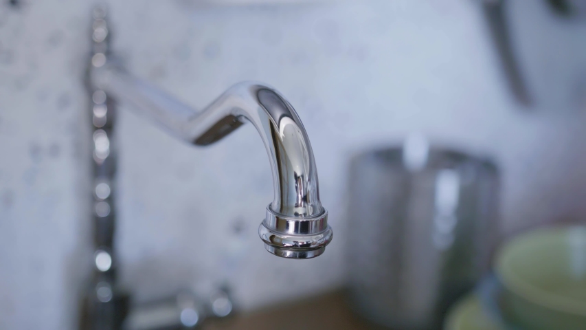 Clean tap water for washing dishes starts flowing from long, cute, new bright, steel tap in light kitchen when someone turned it on in daylight. | Shutterstock HD Video #1032904355
